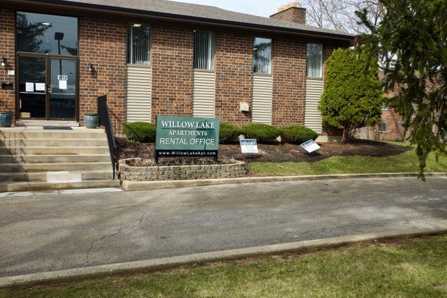 A brick building with a sign that says Willow Lake Apartments Rental Office.